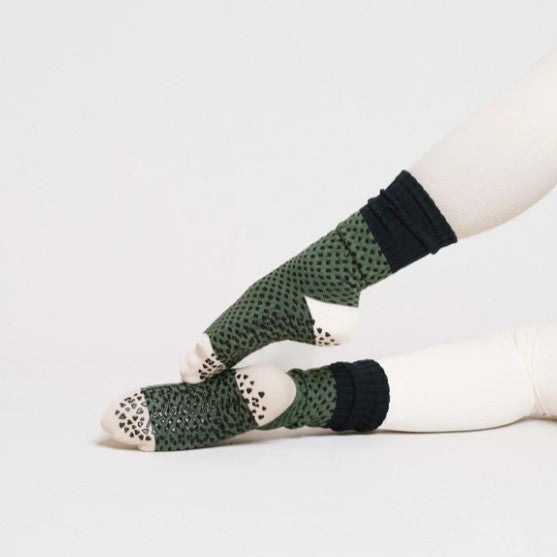 Green patterned socks with black accents worn by a person on a light gray background