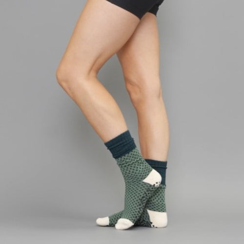 Person wearing green patterned socks with white paws on a gray background