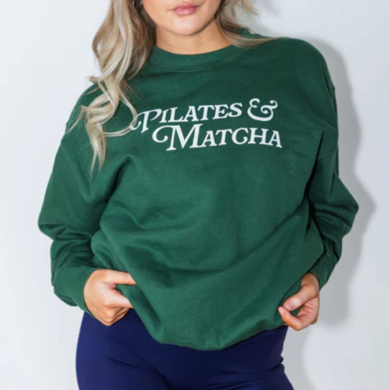 Woman wearing a green sweatshirt with 'Pilates & Matcha' text against a white background