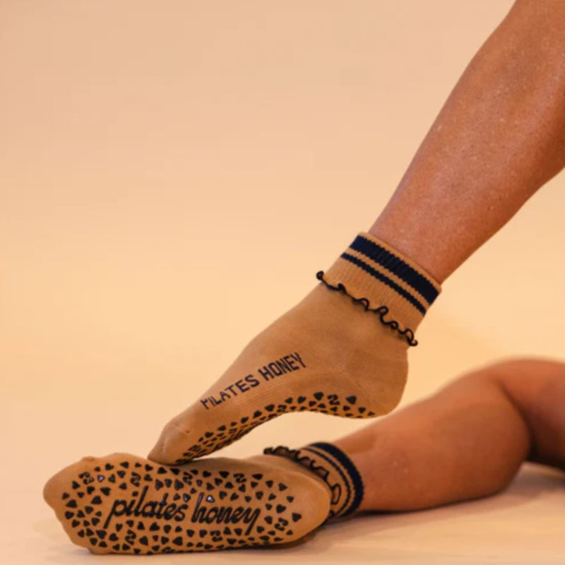 Person wearing Pilates Honey socks with textured soles on a beige background