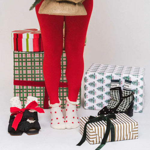 Person wearing red leggings with Christmas-themed decorations and presents.