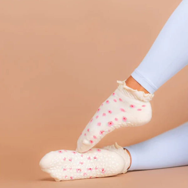 White socks with pink floral patterns worn by a person on a beige background