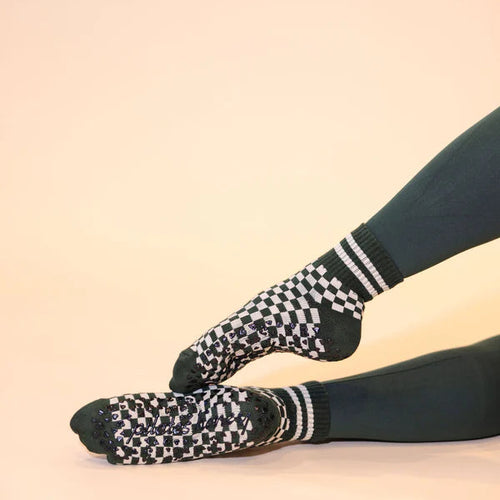 Black and white checkered socks worn with green leggings on a beige background
