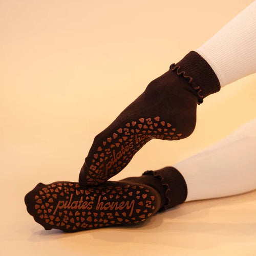 Black Pilates socks with grip texture worn by a person on a beige background