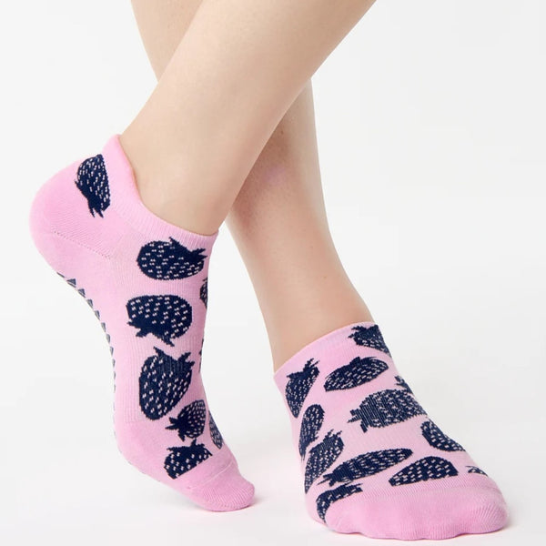 Pink socks with black strawberry patterns worn by a person on a white background