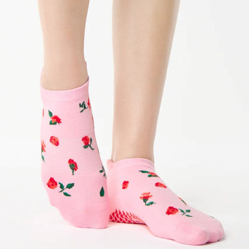 Pink socks with red rose pattern worn by a person on a white background