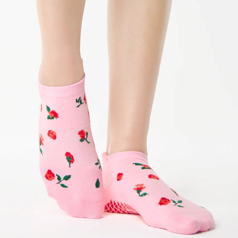 Pink socks with red rose pattern worn by a person on a white background