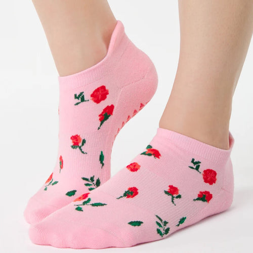 Pink socks with red rose patterns worn by a person on a white background