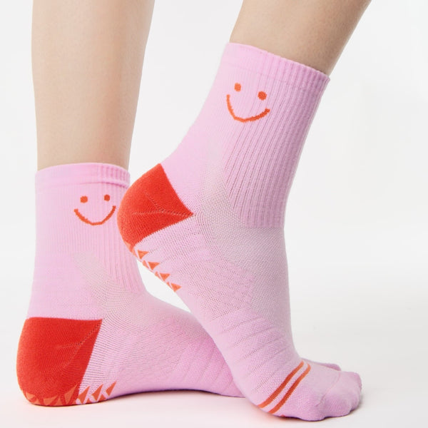 Pink socks with smiley face design worn by a person on a white background