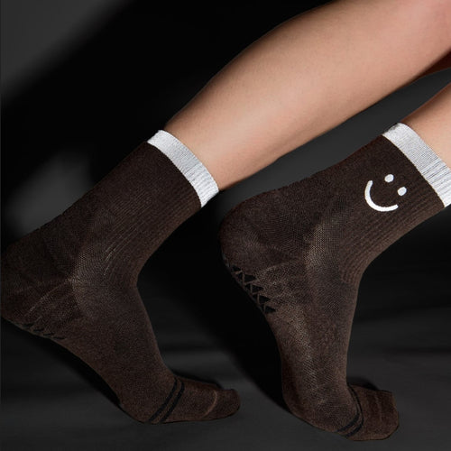 Brown socks with white smiley face design on a dark background
