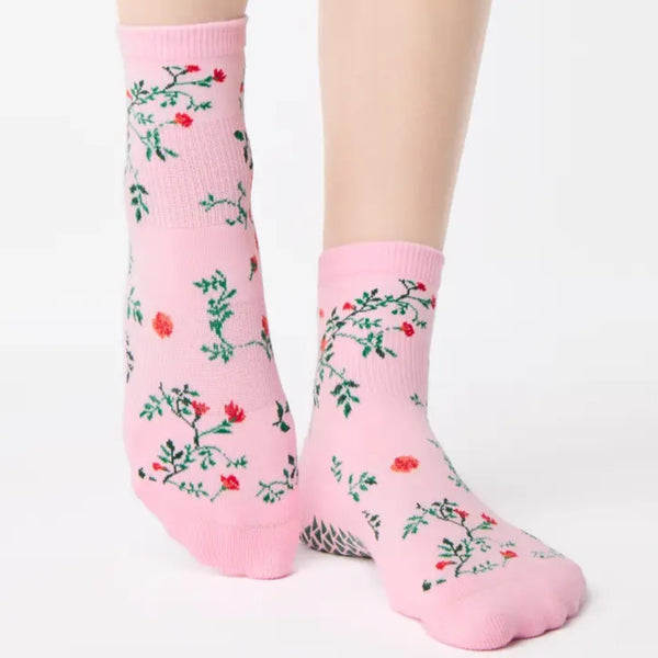 Pink socks with floral patterns worn by a person on a white background