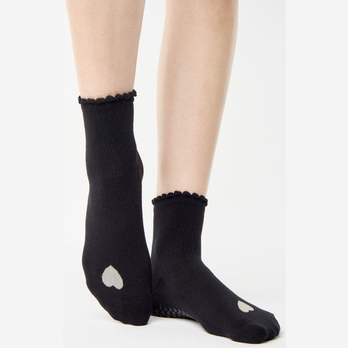 Black socks with heart designs worn by a person on a white background