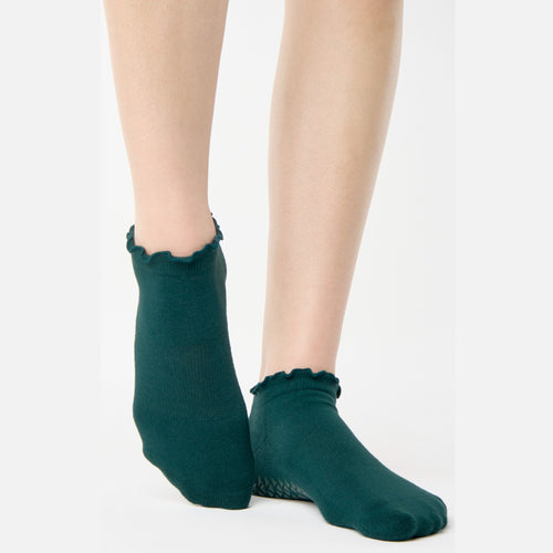 Green socks with ruffled edges worn by a person on a white background