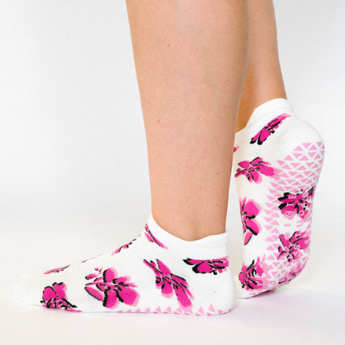 White socks with pink floral patterns worn by a person on a light gray background