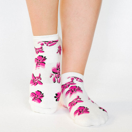 White socks with pink floral patterns worn by a person on a light gray background