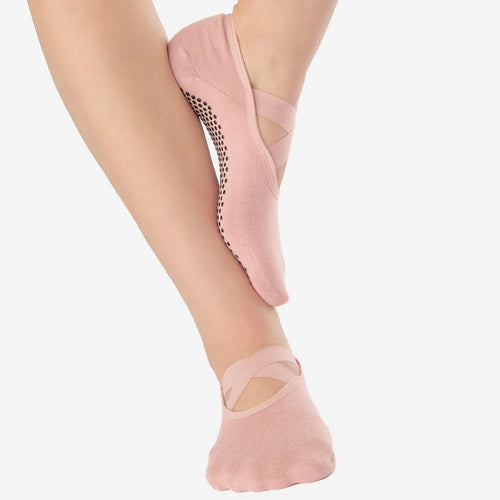 Pink ballet shoes worn by a person on a white background