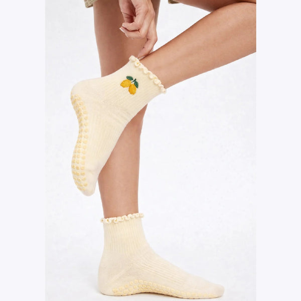 Cream-colored socks with ruffled edges and lemon design on a white background