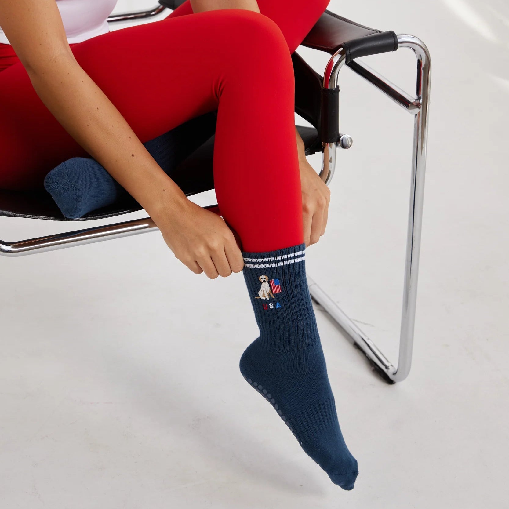 Person wearing red leggings and navy socks with white patterns, sitting on a chair.
