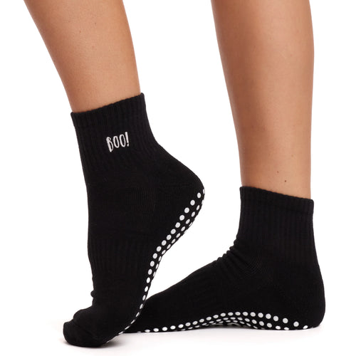 Black socks with white non-slip dots worn by a person on a white background