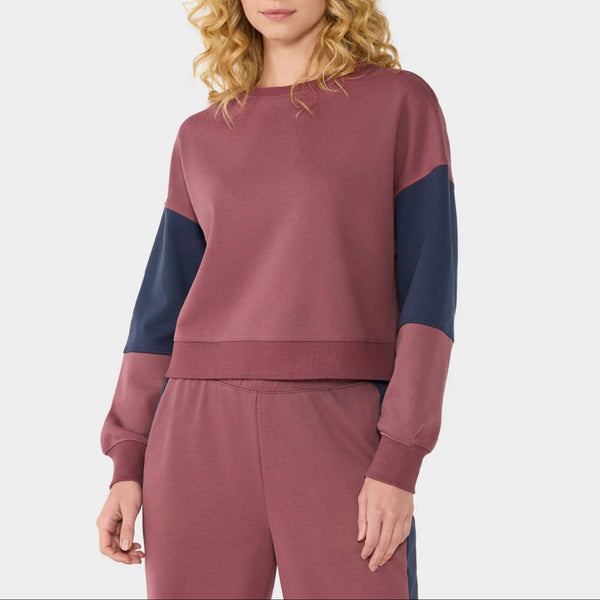 Woman wearing a two-tone maroon and navy sweater set on a white background