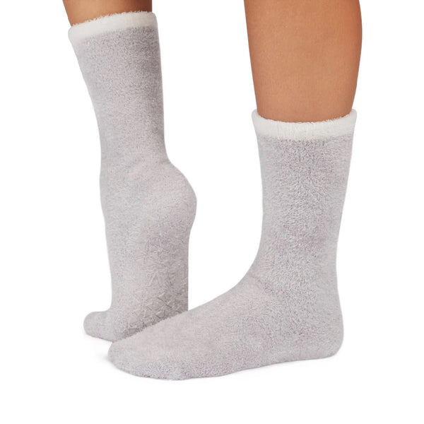 Gray fuzzy socks worn on a white background