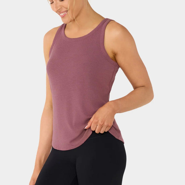 Woman wearing a mauve tank top and black leggings on a white background