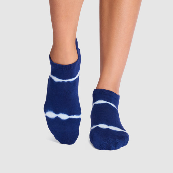 Blue and white tie-dye socks worn by a person on a light gray background