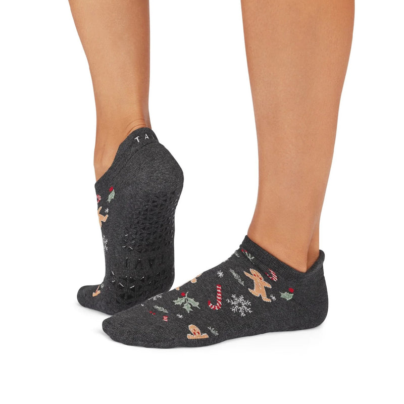 Dark gray ankle socks with winter-themed designs worn by a person on a white background