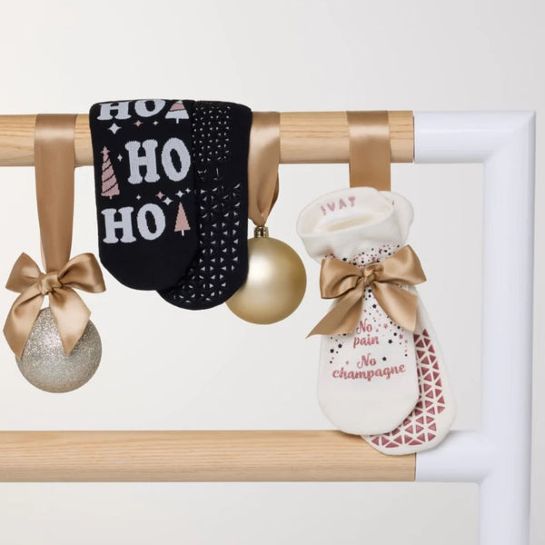 Decorative stockings with festive text and ribbons on a wooden rack.