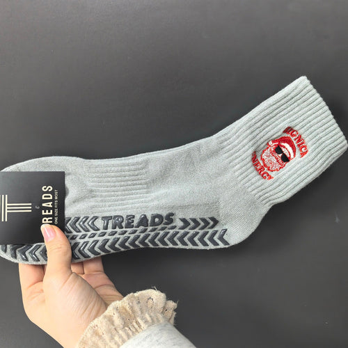Gray sock with branding held by a hand against a dark background