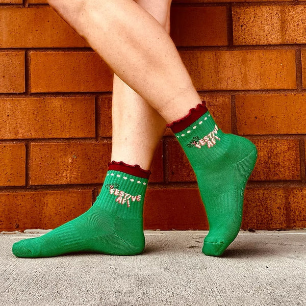 Green socks with text worn by a person against a brick wall.
