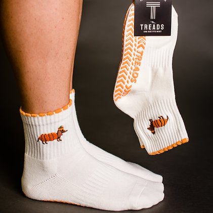 White socks with orange accents and a small dog design, held by a person against a dark background.
