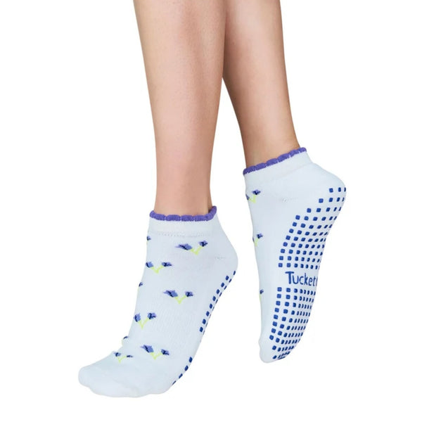 White ankle socks with blue and yellow bird patterns and blue grip dots on the sole, shown on a person's feet against a white background.