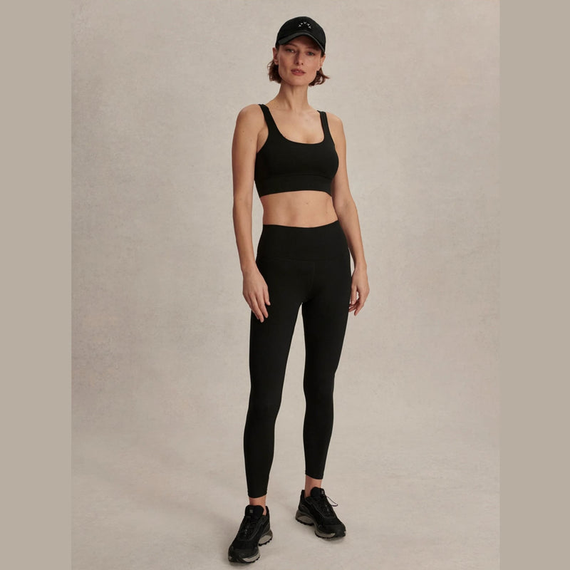 Woman wearing a black sports bra and leggings set on a plain background