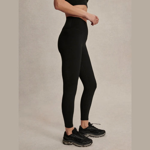 Person wearing black leggings and black sneakers on a beige background